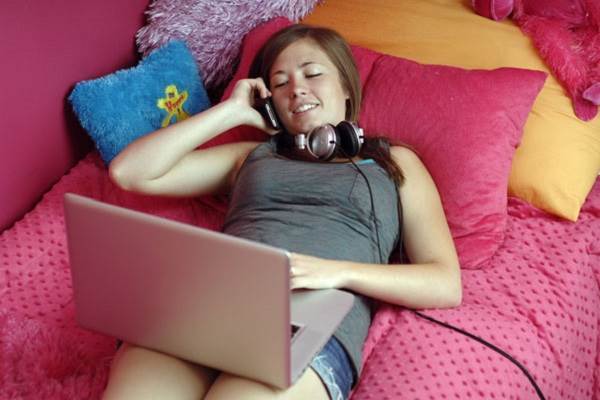 Girl in Shorts Lying on Bed with tech